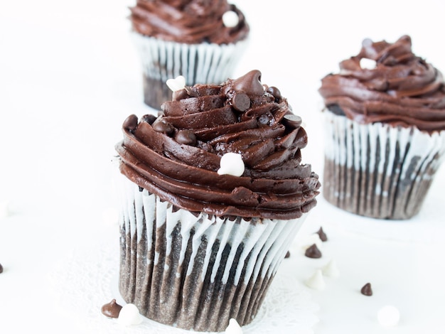 Gourmet quadrupli cupcakes al cioccolato su sfondo bianco.