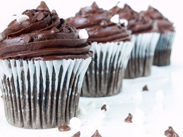 Gourmet quadrupli cupcakes al cioccolato su sfondo bianco.