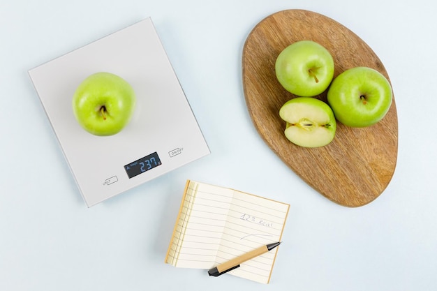 GPT Mela verde sulla bilancia Calorie annotate con mele e penna a bordo Alimentazione sana e pesatura c