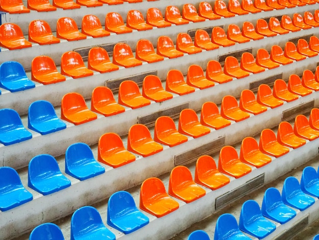 Gradinate posti vuoti sugli spalti dell'arena o dell'auditorium File di sedili blu e arancioni dello stadio senza spettatori Il concetto di abolizione degli eventi sportivi e di intrattenimento di massa