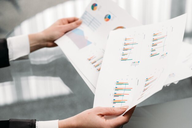 grafici di documenti aziendali. mani che tengono le carte. report statistiche analisi dei dati. posto di lavoro in ufficio