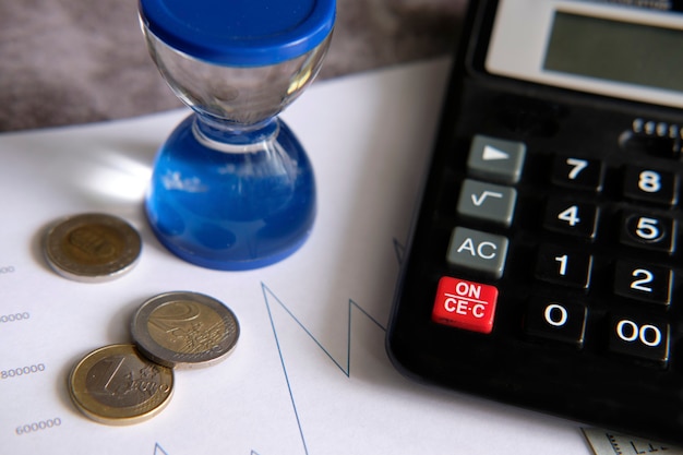 Grafici finanziari accanto a una calcolatrice e ad alcune monete in euro