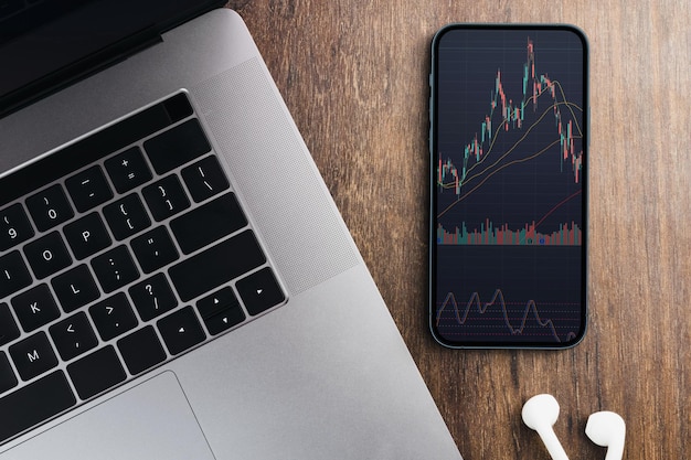 Grafico del mercato azionario finanziario sullo schermo dello smartphone sul tavolo di legno Ambiente d'ufficio Borsa valori