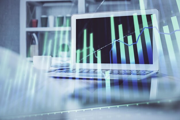 Grafico del mercato azionario sullo sfondo con scrivania e personal computer Esposizione multipla Concetto di analisi finanziaria