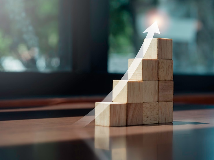 Foto grafico di crescita. incandescente freccia verso l'alto sulla parte superiore dei gradini del grafico a blocchi di legno sulla scrivania in legno con spazio per le copie, stile eco. il processo di crescita aziendale, la finanza e il concetto di miglioramento economico.
