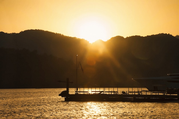 Grana artistica del film di rumore. Tramonto in laguna di azzurro Mar Egeo con montagne lussureggianti, soffici nuvole, yacht, clima estivo. Paesaggio della natura nella Turchia orientale. Concetto di vacanza, svago e viaggio