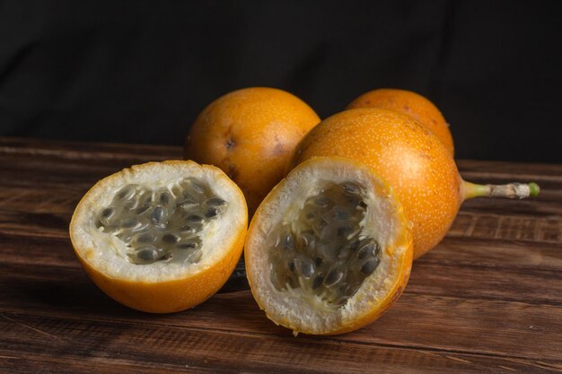 Granadilla dolce o frutto della passione grenadia. Frutti esotici interi e tagliati a metà su tavola di legno