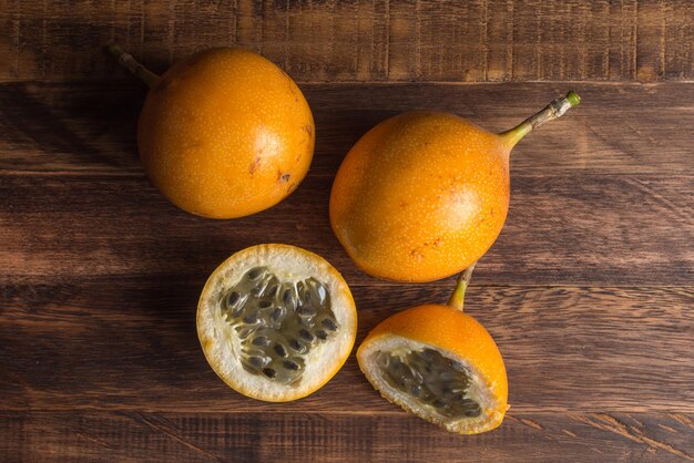 Granadilla dolce o frutto della passione grenadia. Frutti esotici interi e tagliati a metà su tavola di legno