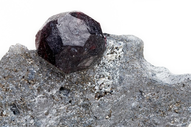 Granato di pietra minerale macro nella roccia su sfondo bianco