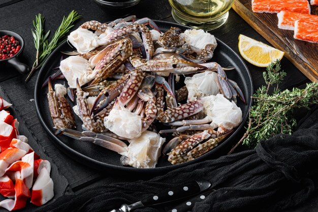 Granchio crudo fresco del fiore o parti del granchio blu messe, sul fondo di legno nero della tavola