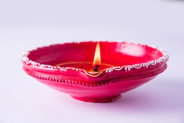 Grande argilla decorativa rossa diya o lampada a olio accesa durante il festival di diwali. Messa a fuoco selettiva