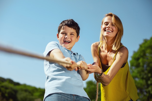 Grande attività. Madre amorevole contenta che aiuta suo figlio mentre tira una corda con sua sorella