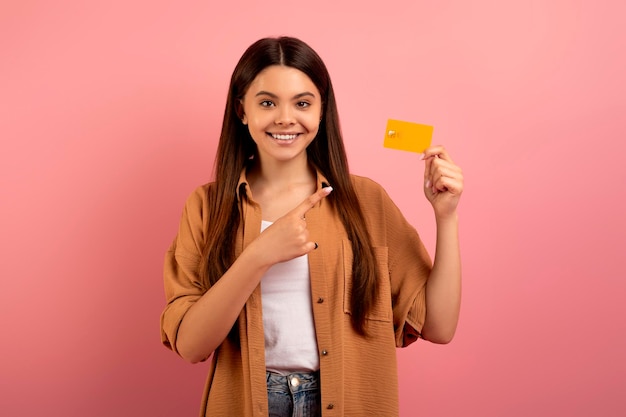 Grande banca ragazza adolescente felice che indica la carta di credito in mano