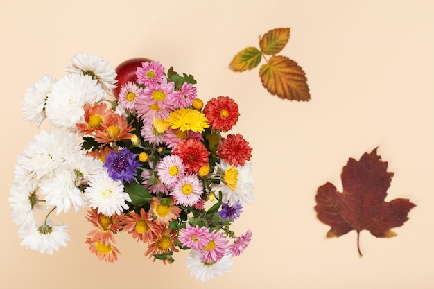 Grande bouquet di fiori colorati diversi e foglie secche sullo sfondo beige. Vista dall'alto.