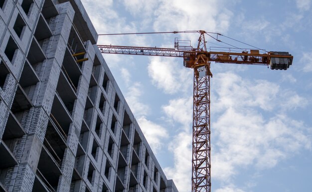 Grande cantiere. Il processo di costruzione del capitale di un complesso residenziale a molti piani. Edificio in cemento, costruzione, sito industriale. Gru industriale sullo sfondo del cielo.