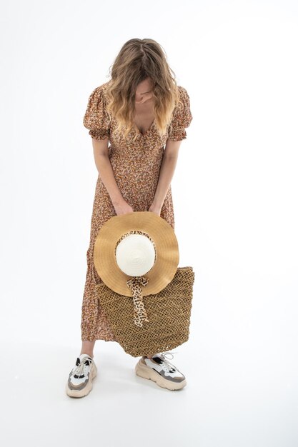 Grande cappello estivo nelle mani di una donna vestita con un abito marrone isolato su sfondo bianco