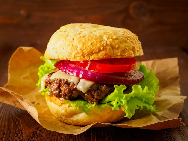 Grande delizioso hamburger fatto in casa con cotoletta di manzo, formaggio, cipolla, pomodoro e lattuga