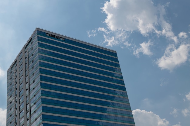 Grande edificio per uffici di vetro con cielo blu e nuvola bianca