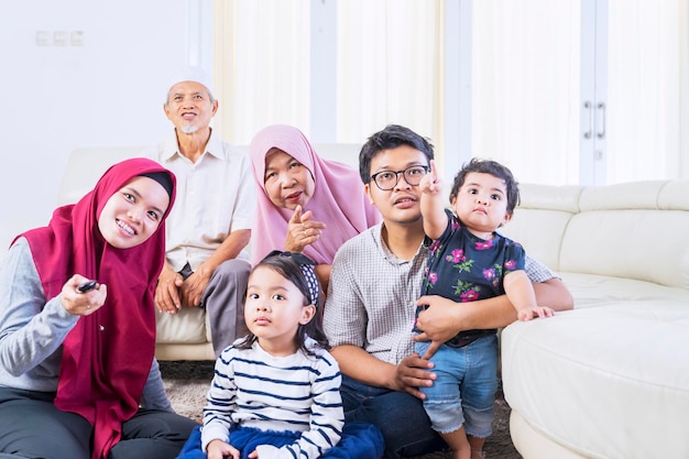 Grande famiglia musulmana che guarda la televisione con gioia