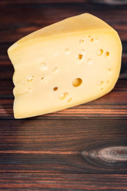 Grande fetta di formaggio svizzero semi molle parzialmente scremato su uno sfondo di legno scuro.