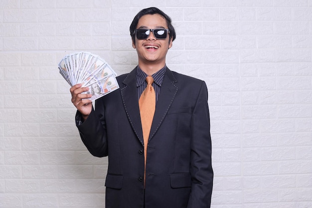 Grande fortuna ragazzo gioioso in vestito che tiene denaro denaro contante profitto e successo finanziario ricco uomo asiatico Showin