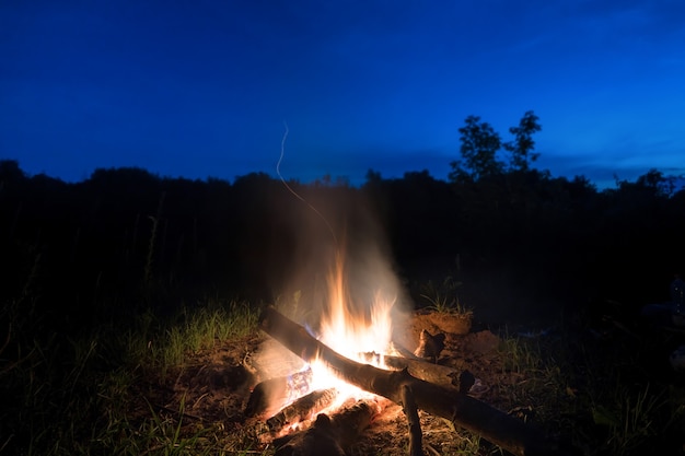 Grande fuoco arancione nel falò al tramonto con cielo notturno blu scuro