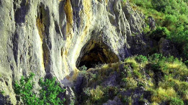 Grande grotta nella roccia, ingresso triangolare di una grotta buia, le montagne della Spagna