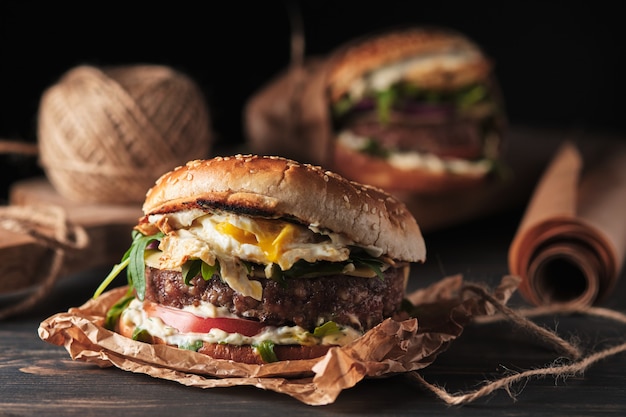 Grande hamburger alla griglia con verdure su una tavola di legno