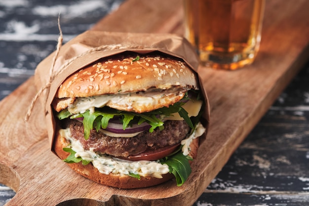 Grande hamburger alla griglia con verdure su una tavola di legno