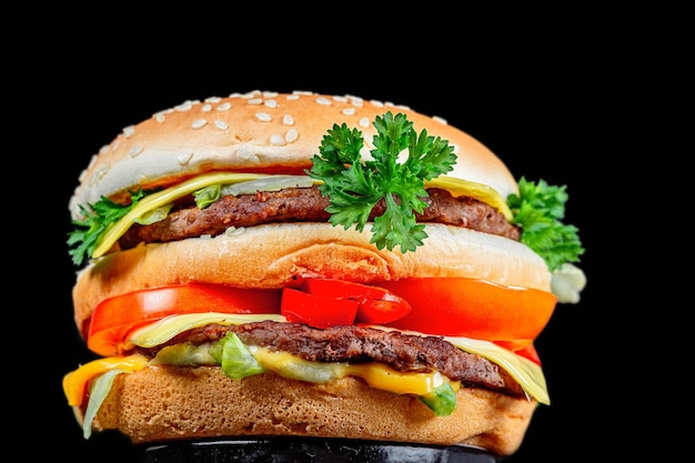 Grande hamburger con verdure e cotolette su uno sfondo nero