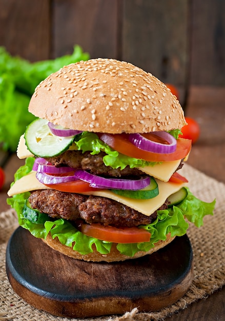 Grande hamburger succoso con verdure e manzo su un tavolo di legno in stile rustico