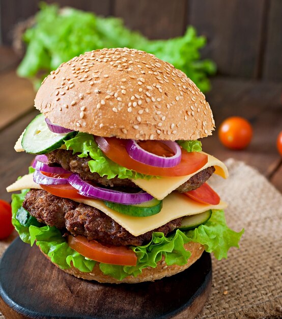 Grande hamburger succoso con verdure e manzo su uno sfondo di legno in stile rustico