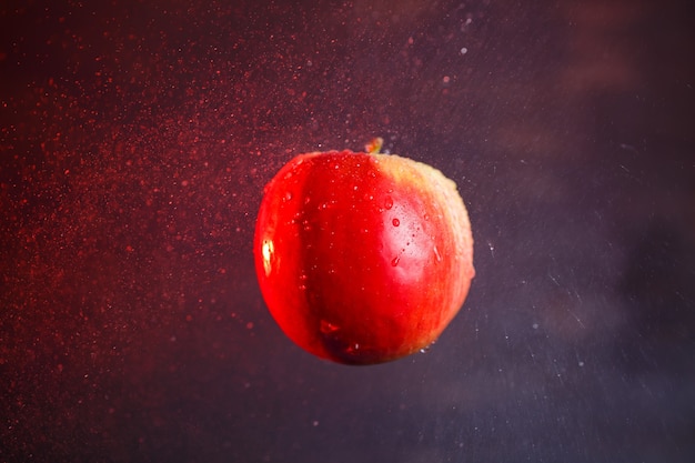 Grande mela rosso-gialla, inondata d'acqua su uno sfondo scuro