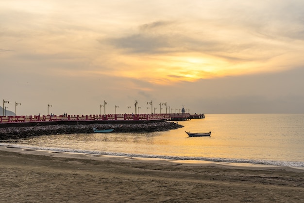 Grande molo sul mare al tramonto e una barca in Thailandia