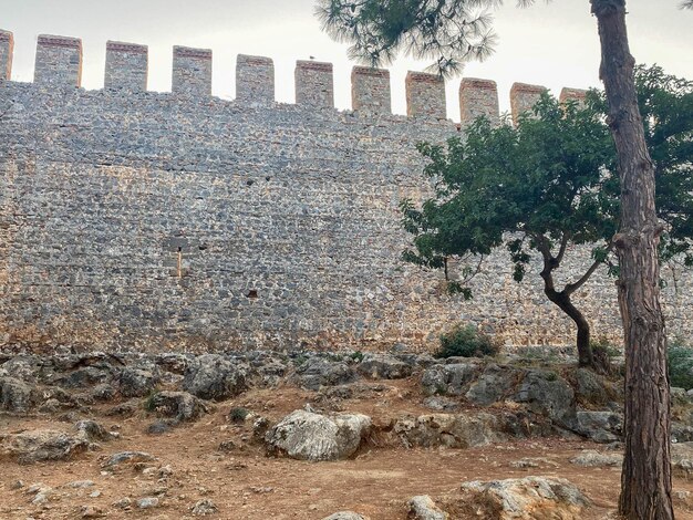 Grande muro di pietra di un'antica fortezza medievale fatta di ciottoli contro un cielo blu