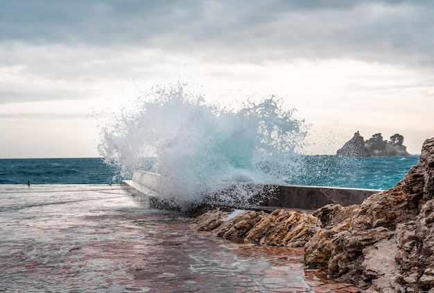 Grande onda splash sul molo Grande onda del mare in una giornata ventosa Le onde si infrangono contro il frangiflutti in cemento all'ingresso del porto Onde giganti che si infrangono sul frangiflutti