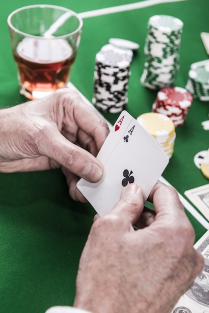 Grande opportunità. Primo piano di un uomo che tiene in mano le carte mentre è seduto al tavolo da poker con un sacco di fiches e denaro su di esso