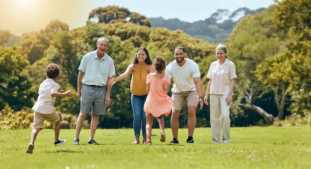 Grande parco naturale per famiglie e felice di giocare con i bambini che corrono sull'erba con i nonni anziani mamma e papà sorridono sotto il sole estivo Divertente madre padre e braccia aperte per abbracciare insieme i bambini all'aperto