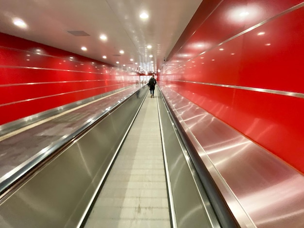 Grande passerella sotterranea lunga e luminosa rossa moderna tra le stazioni della metropolitana con i camminatori di viaggio