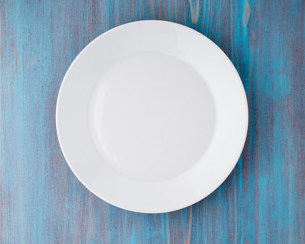 Grande piatto bianco vuoto piatto su un tavolo in legno blu, vista dall&#39;alto