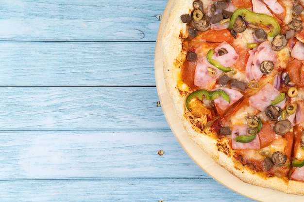 Grande pizza deliziosa con vitello e funghi su un fondo di legno blu