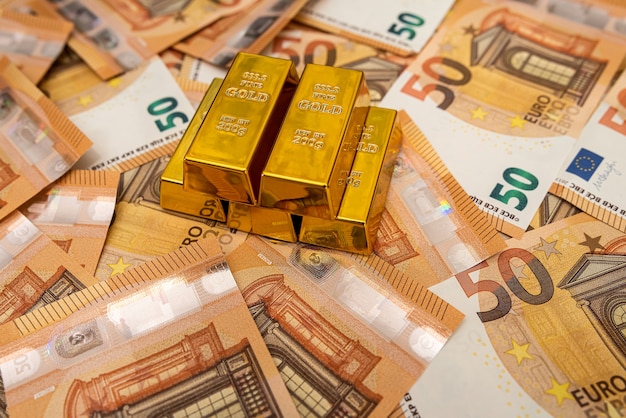 Grande quantità di banconote in euro e concetto di risparmio di lingotti d'oro