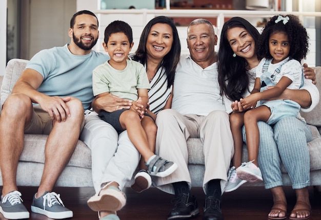 Grande ritratto di famiglia sul divano di casa soggiorno insieme in Messico e felice ragazza afro-latino seduta sulle ginocchia della mamma I nonni anziani amano i bambini piccoli padre orgoglioso sorriso e felicità generazioni