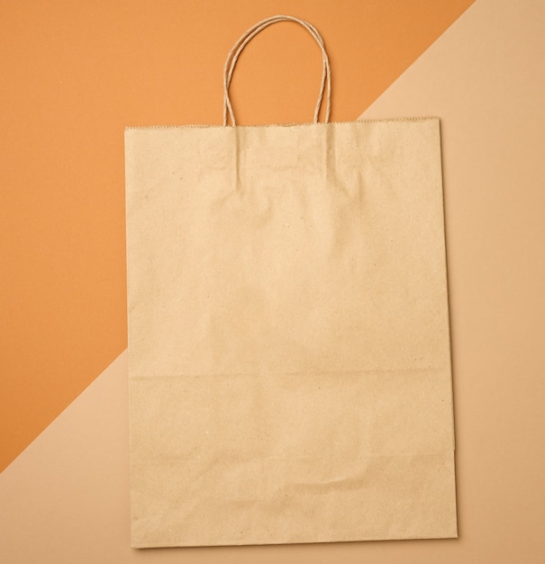 Grande sacchetto di carta kraft marrone usa e getta con manici su sfondo marrone, imballaggio ecologico, zero rifiuti