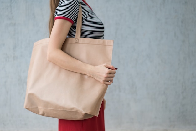Grande shopping bag ecologica sulla spalla di una giovane donna. Spazio di progettazione