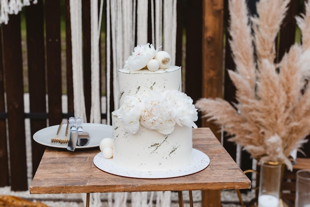 Grande torta nuziale di lusso su uno sfondo di un bellissimo arco in stile boho