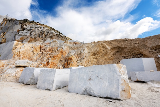 Grandi blocchi tagliati di marmo bianco di Carrara in una miniera o cava a cielo aperto in Toscana, Italia in attesa di trasporto