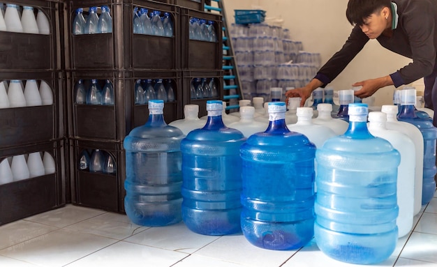 Grandi bottiglie di plastica o litri bianchi e blu di acqua potabile purificata all'interno della linea di produzione