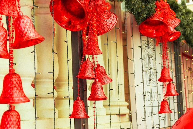 Grandi campane di Natale rosse con fiocchi, luci, rami verdi del primo piano dell'albero di Natale. Anno nuovo 2021 e Natale, umore del nuovo anno, decorazioni del nuovo anno
