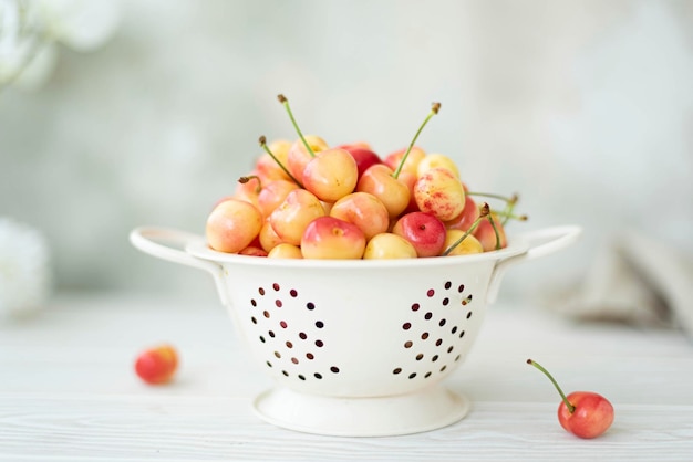 Grandi ciliegie rosa mature in uno scolapasta bianco